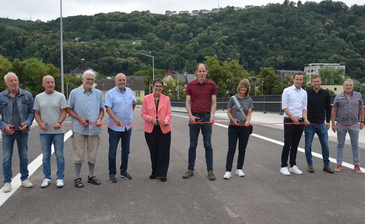 Dietmar Gierse (Fritz Meyer GmbH), Christof Schuh (Bauunternehmung Peter Keren). Stadtratsmitglied Rainer Lehnart, Bernhard Hügle (stv. Ortsvorsteher Trier-West/Pallien), Staatssekretärin Petra Dick-Walther, Baudezernent Dr. Thilo Becker, Christa Klein (SBS-Ingenieure), Julian Lehnart, Eric Wolff und Thomas Adler (alle Stadt Raum Trier, v. l.) durchschneiden auf der Fahrbahn der neuen Brücke das Band zur Verkehrsfreigabe.