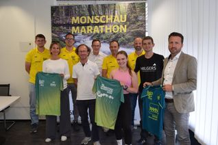 Johannes Wergen, Philipp Banzet, Philipp Nickel, Thomas Rubel und Oliver Krings vom TV Konzen (hintere Reihe von links) freuen sich gemeinsam mit Yvonne Rollesbroich (2.v.li., EWV) und Christian Reinartz (re., Sparkasse Aachen), die beim Pressetermin die Hauptsponsoren vertraten, auf die 48. Auflage des Monschau-Marathons. Zum hochkarätigen Starterfeld gehören unter anderem Rekordsieger André Collet (4.v.li.), die Aachener Lauf-Influencerin Veronika Stockem und Lokalmatador Max Schreiber (2.v.re., TV Konzen), die sich ebenfalls auf das Marathon-Wochenende freuen. Foto: Scholl