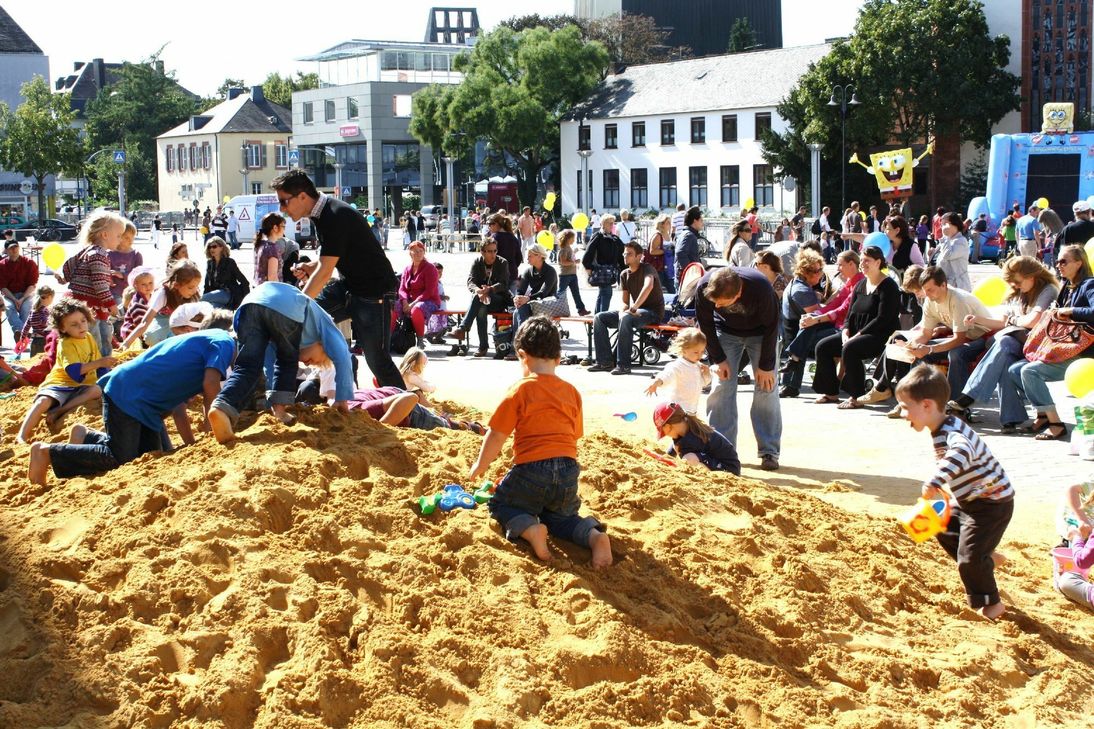Der Riesen-Sandkasten auf dem Viehmarkt ist ein beliebter Treffpunkt für Familien mit Kleinkindern, die hier nach Herzenslust wühlen, buddeln und Freunde treffen können. Einen Überblick über die vielfältigen Spielaktionen bietet hier der Infostand der City-Initiative. Foto: Archiv