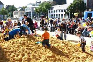 Der Riesen-Sandkasten auf dem Viehmarkt ist ein beliebter Treffpunkt für Familien mit Kleinkindern, die hier nach Herzenslust wühlen, buddeln und Freunde treffen können. Einen Überblick über die vielfältigen Spielaktionen bietet hier der Infostand der City-Initiative. Foto: Archiv