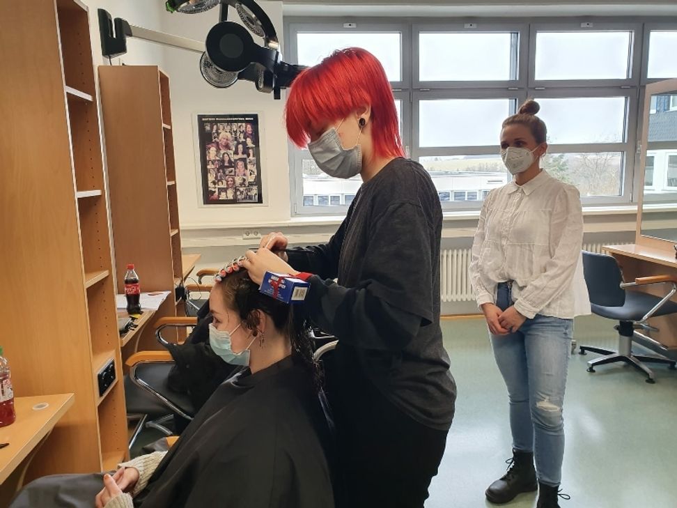 Bevor es wieder losgeht werden die Friseur-Auszubis geprüft. Das Foto zeigt Prüferin und Lehrerin Anna Abidi (rechts) und Prüfling Camilla Kreer. (Foto: Kreishandwerkerschaft)