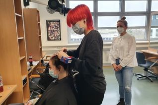 Bevor es wieder losgeht werden die Friseur-Auszubis geprüft. Das Foto zeigt Prüferin und Lehrerin Anna Abidi (rechts) und Prüfling Camilla Kreer. (Foto: Kreishandwerkerschaft)