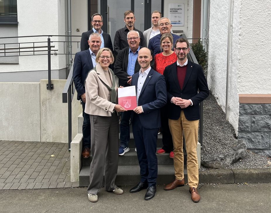 Staatssekretärin Simone Schneider (vorne links) übergibt den Förderbescheid an Thomnas Scheppe (vorne Mitte), den Bürgermeistger der VG Daun.