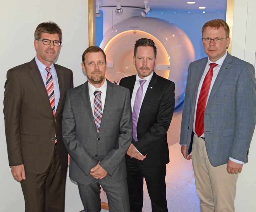 Prof. Michael Jäckel, Prof. Gregor Domes, Prof. Winfried Willinek und Markus Leineweber (von links) vor einem Magnetresonanztomograph. Foto: Uni Trier