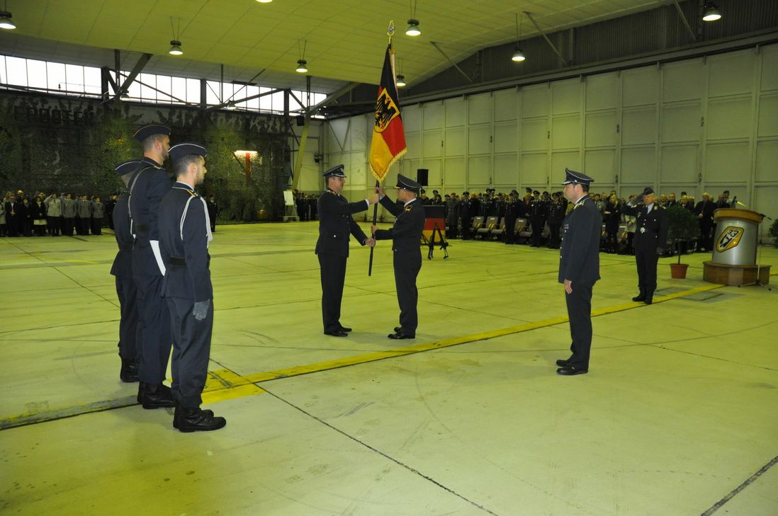 Oberst Andreas Korb übergibt die Truppenfahne an Brigadegeneral Günter Katz, der sie an Oberstleutnant Holger Radmann weiterreicht.