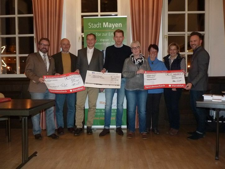 Schecks für den guten Zweck (von links): Oberbürgermeister Wolfgang Treis, Hans-Jürgen Sittig, Michael Kaltz ("Kreissparkasse Mayen"), Timo Schlich ("Volksbank RheinAhrEifel"), Inge Michels-Proft, Doris Brixius und Lilli Samson (Vertreterinnen der Mayener Tafel / Caritasverband) sowie Guido Braun (WochenSpiegel).