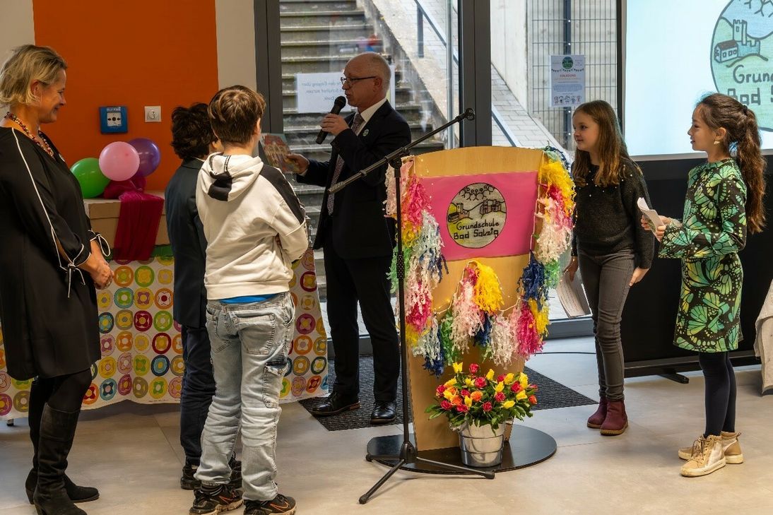 Schulleiterin Barbara Lautwein-Gromes (links) und Bürgermeister Jörg Haseneier mit den vier Kindermoderatorinnen und -moderatoren, die beim Festakt durch das Programm führten