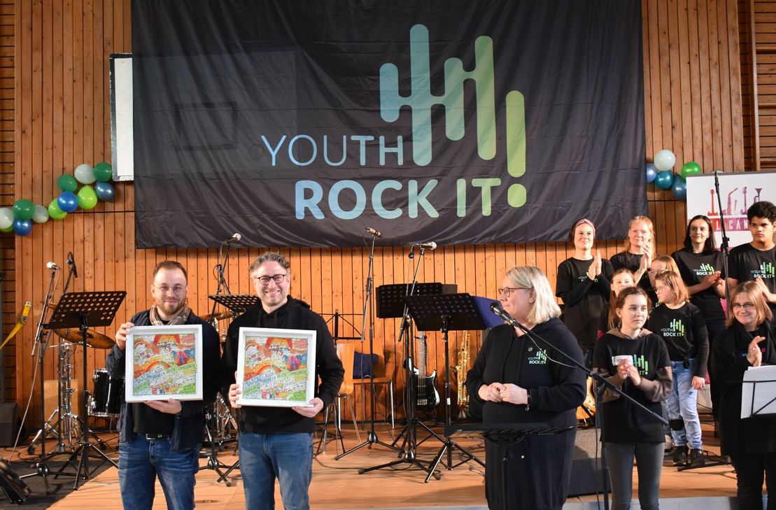 Sebastian Dzienudda-Pesch (links) und Timo Mattes (rechts) aus dem Vorstandsteam des gemeinnützigen Vereins erhalten als Dankeschön ein kleines Präsent.