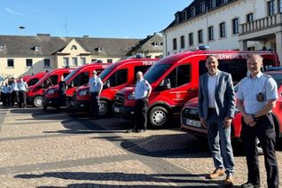 Die Freiwilligen Feuerwehren haben die neuen Fahrzeuge auf dem Marktplatz aufgestellt: (v.r.) Wehrleiter Mario Gaspar und der hauptamtliche Beigeordnete Guido Wacht mit Kommandowagen, den sechs neuen Mannschaftstransportfahrzeugen und dem neuen Mehrzweckboot.