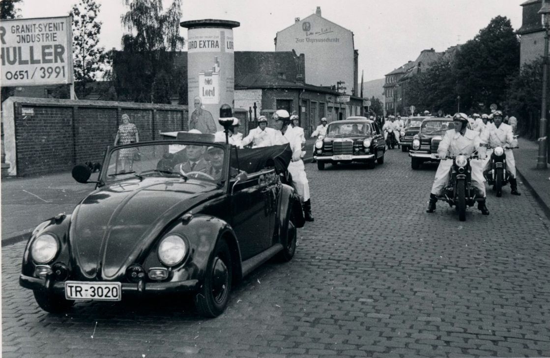 Wie der Zufall es wollte, fand sich in einem Bildband über Dienstfahrzeuge der Polizei tatsächlich ein Foto, genau dieses VW Käfer Cabrios, aus dem Jahr 1966. Weitere Recherchen ergaben, dass das Foto, welches im Hintergrund eine Fahrzeugkolonne zeigt, anlässlich des Staatsbesuches von Konrad Adenauer am 30. Juni 1966 in der Trierer Thyrsusstraße aufgenommen wurde.