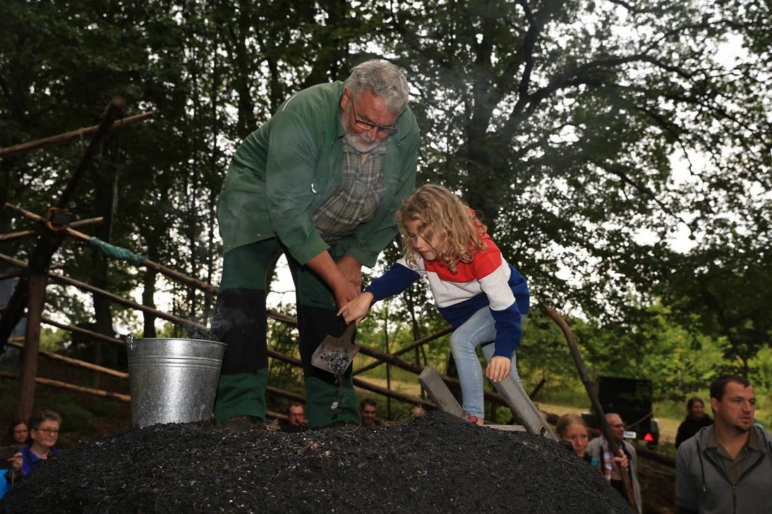 Ein großer Moment - mit Glut entfachen die Kinder den Meiler.