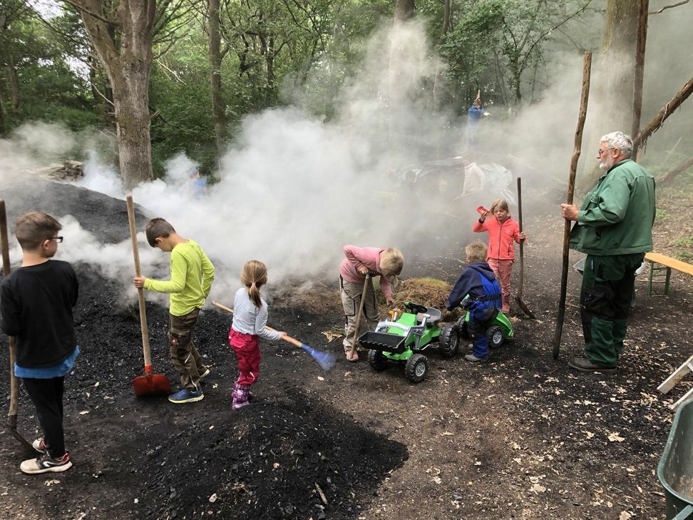 Mit Feuereifer sorgen die 24 Kinder im Alter zwischen zwei und zehn Jahren für »ihren« Kindermeiler. Der erfahrene »Opa« Gerd Linden (re.) führt souverän die Oberaufsicht. mn-Foto