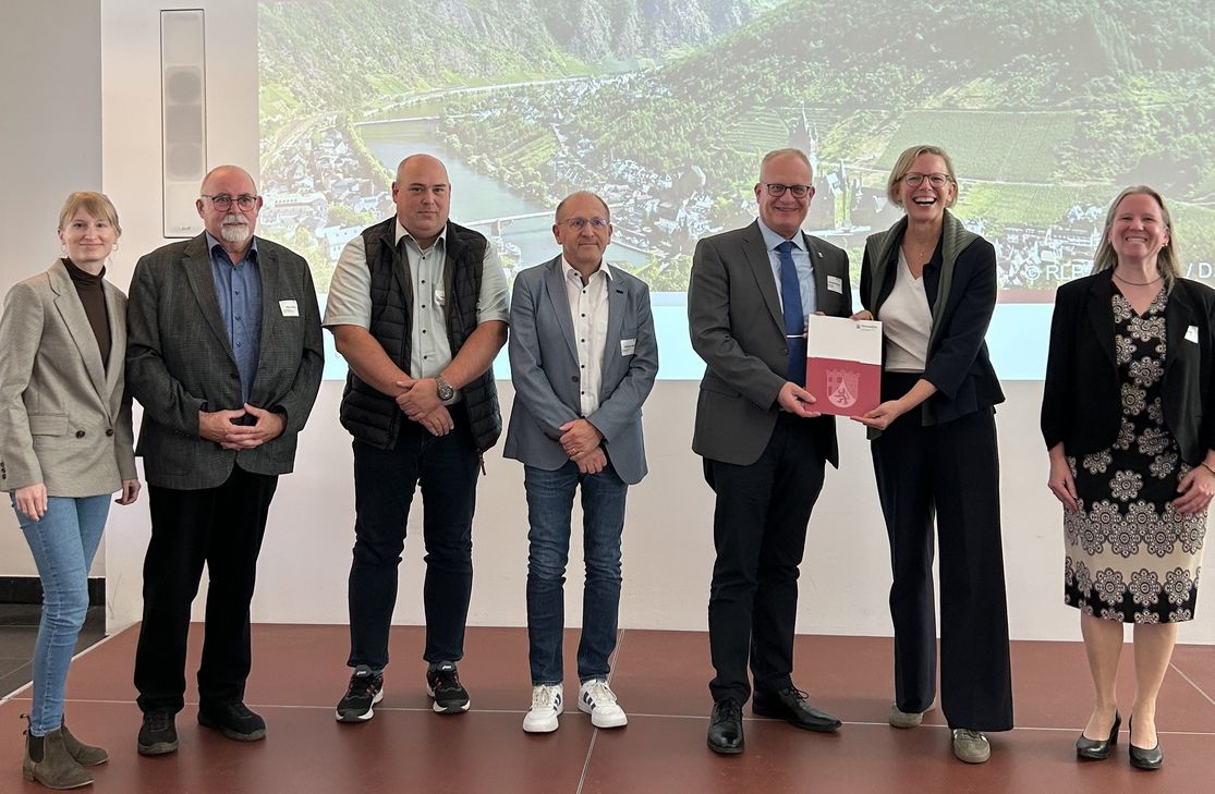 Im Rahmen der Jahrestagung „Interkommunale Zusammenarbeit“ in Mainz überreichte Staatssekretärin Simone Schneider (2.v.r.) den Förderbescheid über 370.000 Euro an Bürgermeister Michael Holstein (3.v.r.). Begleitet wurde er von (v.l.n.r.) Sachbearbeiterin Tamara Ulrich, Ortsbürgermeister Peter Bruns (Langsur), Beigeordnetem Marcel Keilen, Fachbereichsleiter Matthias Wagner und Beigeordneter Daniela Nöhl.