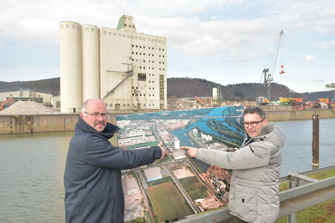 Volker Klassen (rechts) mit Hafenmeister Stefan Jakobi mit einem Foto von 2007, auf dem die beiden auf die gerade entstehende Freifläche zeigen. Im Hintergrund der weichende alte Kornspeicher.