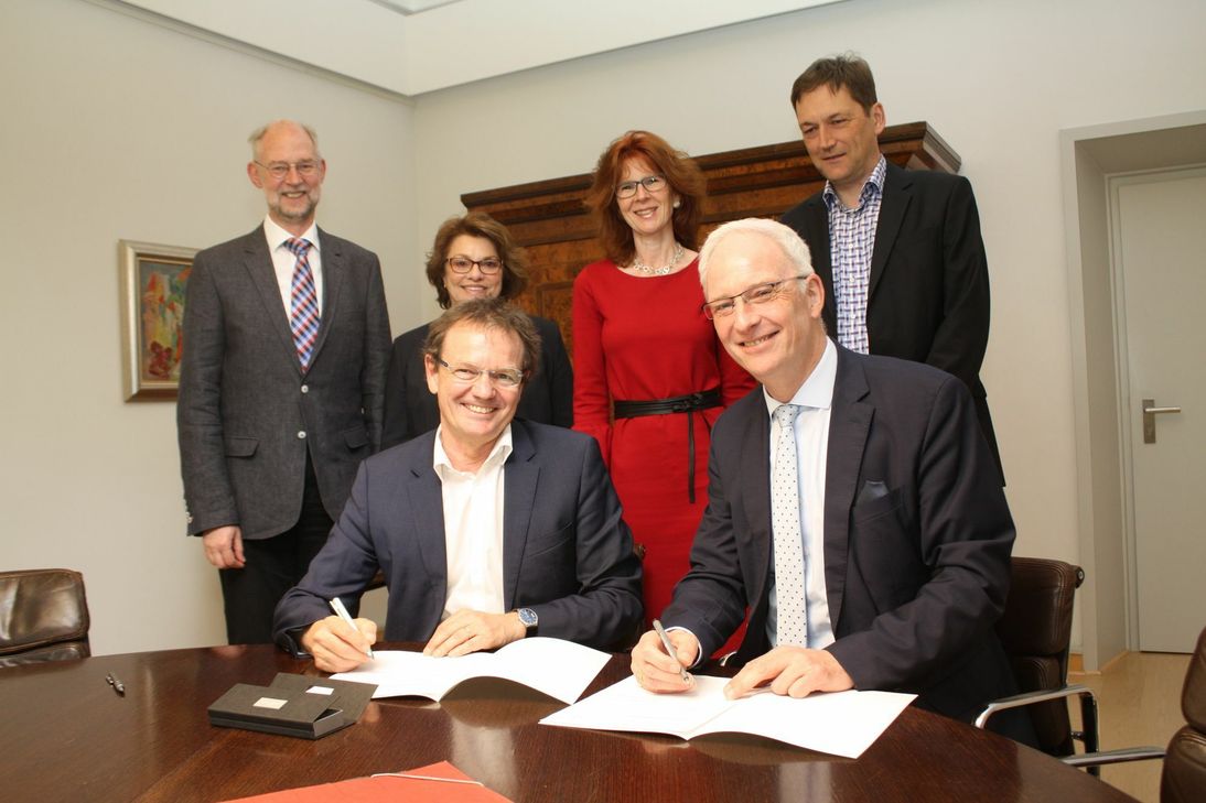 Prof. Norbert Kuhn und OB Wolfram Leibe setzen ihre Unterschrift unter den Kooperationsvertrag. An der Zusammenarbeit waren außerdem beteiligt: Prof. Andreas Künkler von der Hochschule und Beate Weiland, Petra Steinbach und Jörg Lamberti vom Rathaus (v. l.). Foto: Presseamt Trier