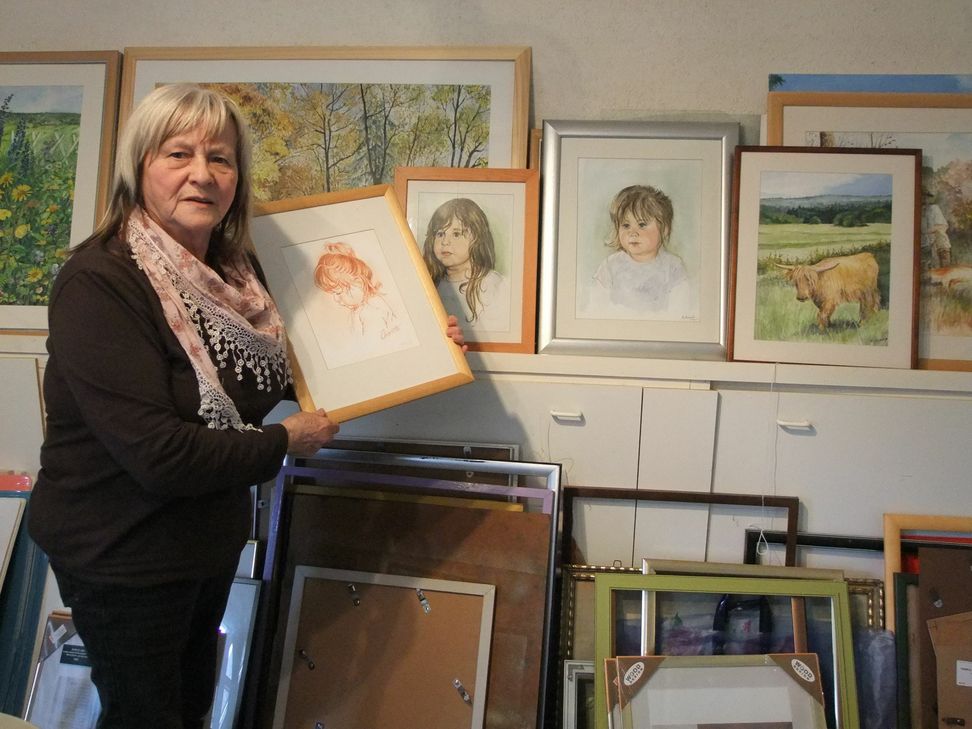 Neben der Familie Atayi engagiert sich die Künstlerin auch für Flüchtlinge in der AfA Hermeskeil. Bei ihrer letzten Aktion gab es für jeden gespendeten Kinderwagen ein Porträtbild, so wie das, das sie hier auf dem Foto in ihrem Atelier zeigt. Foto: Fischer