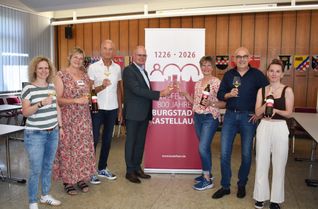 Mit dem Jubiläumswein stoßen Christian Keimer und Jutta Neumann, zusammen mit Vertretern der Stadtrates und der Tourist-Info an.