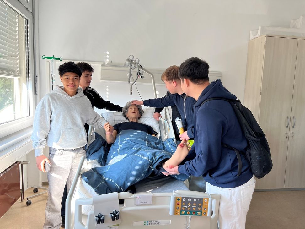 esucherinnen und Besucher testen praktische Tätigkeiten aus, hier bei einer Übung aus der Krankenpflegeausbildung.