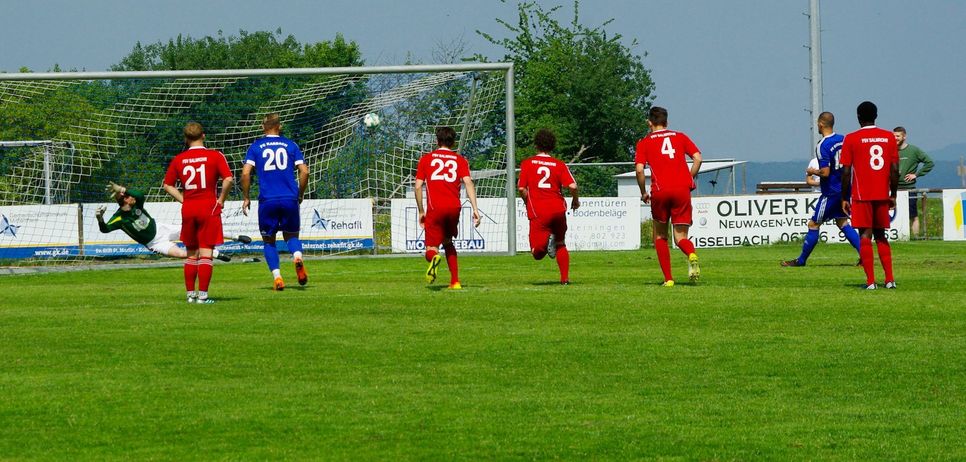 In seinem letzten Heimspiel für den FC Karbach setzte Yannick Rinker (blaues Trikot rechts) in der vierten Minute den Strafstoß platziert ins Salmtaler Tor. Am Ende stand es 2:2. (Foto: Arno Boes)