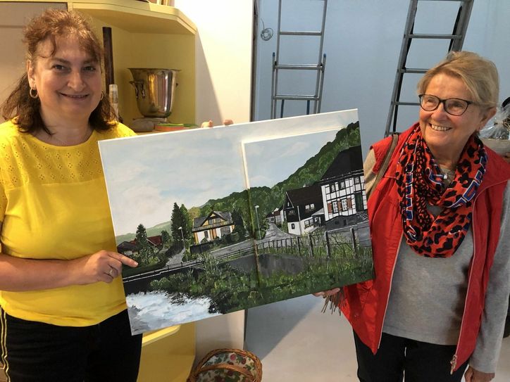 Eine Nachbarin überreichte Marianne Paulson (li.) ein Bild, welches das Haus des Ehepaars vor dem Brand zeigt.