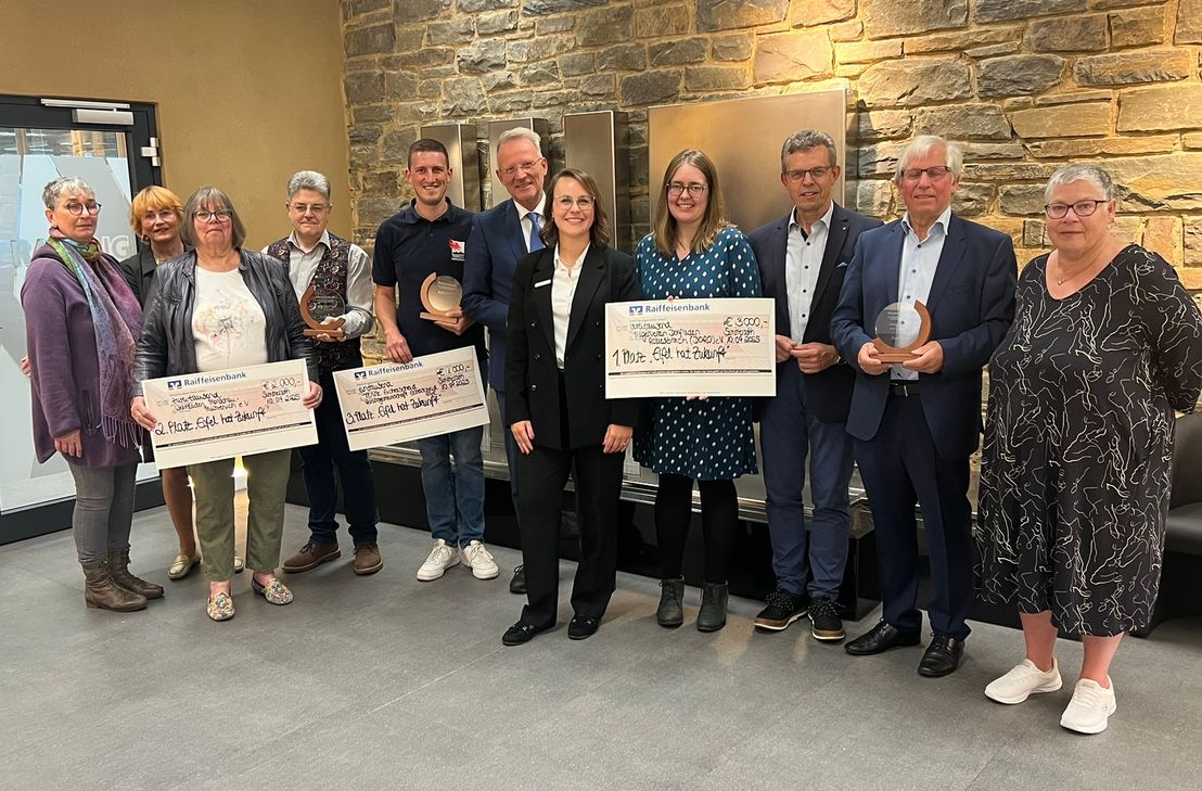 Vertreter von Weltladen Mützenich, Tenne Eicherscheid und Dorfladen Rollesbroich mit Raiffeisenbank-Vorstand Olaf Jansen (6.v.l.) und Alena Voßen (Vorstandsreferentin und Nachhaltigkeitsmanagerin, 5.v.r.) bei der Preisverleihung.