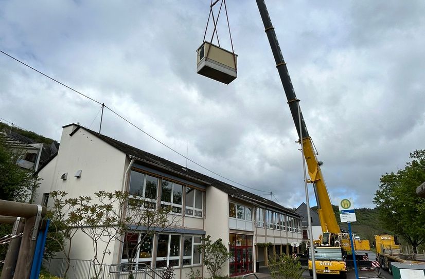 Hier war Präzisionsarbeit gefragt.Netzbetreiber Westnetz stellte die neue 10-Tonnen schwere Trafostation in Reil auf und musste dafür das Großgerät über das Schulgebäude heben.