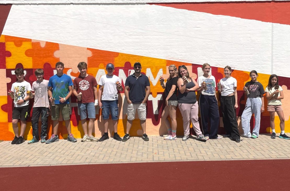 Die Teilnehmer des Graffiti-Workshops vor der fertigen Mauer.