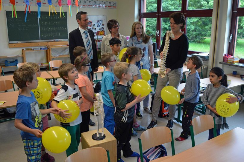 Bild: Durch das Gesundheitsförderprogramm „Klasse 2000“ lernen auch die Schülerinnen und Schüler der Klasse 1 der Grundschule Igel viel über ihren Körper und eine gesunde Lebensweise. Heute übergaben Repräsentanten von RWE gemeinsam mit der Schulleitung und Projektmitarbeitern einen Scheck über eine Spende zur Unterstützung des gesundheitsorientierten Unterrichts.