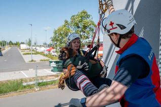 Entspannt liegt der junge Boxer-Rüde Winnie Puuh in den Armen von Karina Boszke während sie im Seil hängt unterstützt von Bergwacht-Leiter Jonathan Klinkhammer.   Foto: Ronald Larmann/pp/Agentur ProfiPress