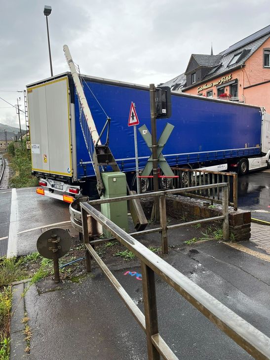 Der lange LKW stand auf dem Bahnübergang und beschädigte dabei die Schrankenanlage. Derzeit wird der Unfall von der Polizei aufgenommen.