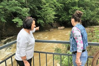 Diana Kebschull (li.) berichtet Mitarbeiterin Tanja Lützig von der Unglücks-Nacht. Nur noch zwei Betonpfeiler erinnern an die Brücke zum beliebten Ausflugslokal Alte Pleiner Mühle. Die gute Nachricht: Die Gaststätte ist auch von der anderen Seite erreichbar und weiter geöffnet. Foto: S. Baumann