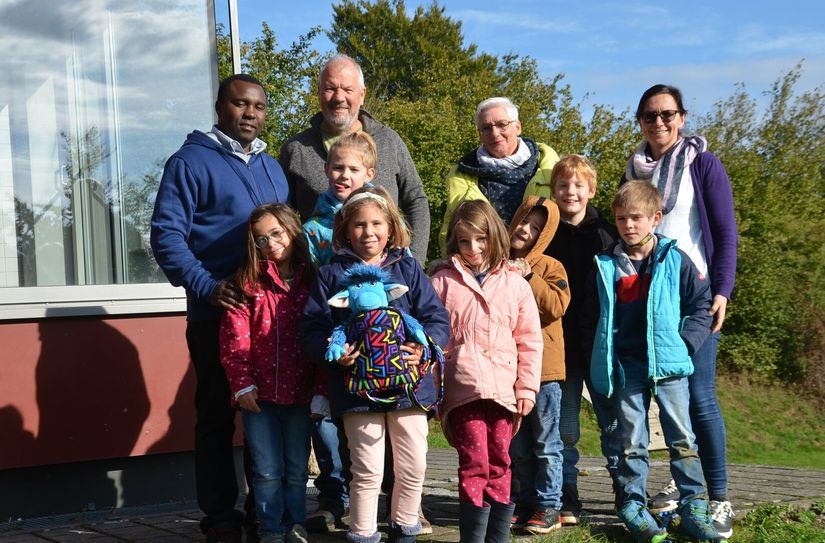 Die Kinder der Förderschule Nordeifel waren fasziniert von dem, was Jean Pierre Munyaneza (l.) aus Ruanda berichtete. Der Klassentroll geht im Rucksack nun mit auf die Reise nach Ruanda und wird nach seiner Rückkehr mit Edith Mertens (hinten, 2.v.r.) berichten, wie das Zentrum für geistig behinderte Kinder in Ruanda vorankommt. Foto: T. Förster