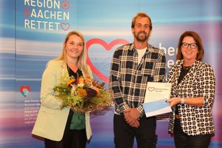 Ulla Thönnissen mit Laura Löbb und Michael Heck, die für den Garten- und Landschaftsbau H. Müller die Auszeichnung der Initiative »Region Aachen rettet« entgegen nahmen. Sie wurden für die Finanzierung eines Defibrillators in Rollesbroich geehrt.