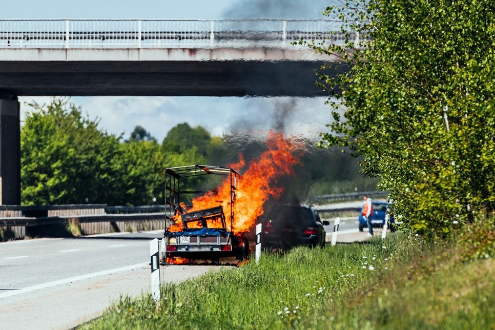 Dem Fahrer gelang es noch, den brennenden Anhänger vom Fahrzeug zu trennen und so ein Übergreifen der Flammen auf den PKW zu verhindern. (Foto: Dennis Irmiter, Fotodokumentator Feuerwehr Rhein-Hunsrück-Kreis)