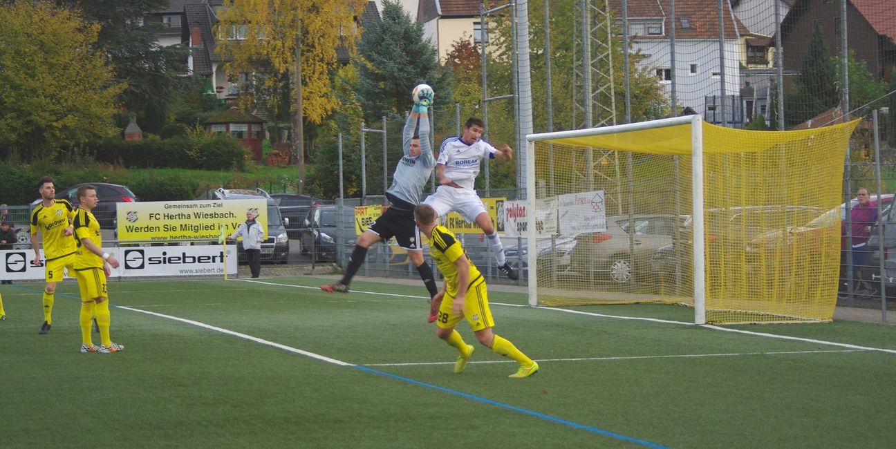 Bei Standards kommt der lange David Eberhard (weißes Trikot) immer mit nach vorne, in dieser Szene kann aber Wiesbachs Torwart Wamsbach den Ball gerade noch abfangen. Foto: Arno Boes