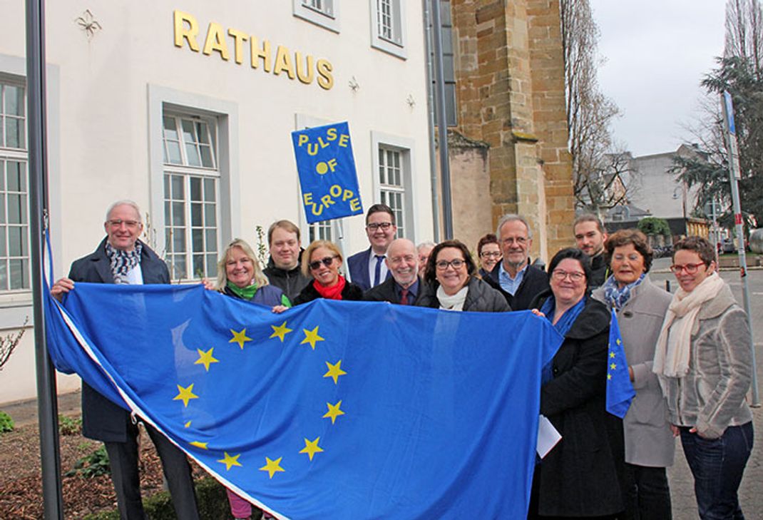 OB Wolfram Leibe (l.), Staatssekretär a.D. Franz Peter Basten (6. v. l.) und "Pulse of Europe"-Mitglied Professor Christel Baltes-Löhr (3. v. r.) setzen gemeinsam mit Vertretern der Stadtratsfraktionen und weiteren "Pulse of Europe"-Mitgliedern mit dem Hissen der europäischen Flagge ein Zeichen für Europa. Foto: FF