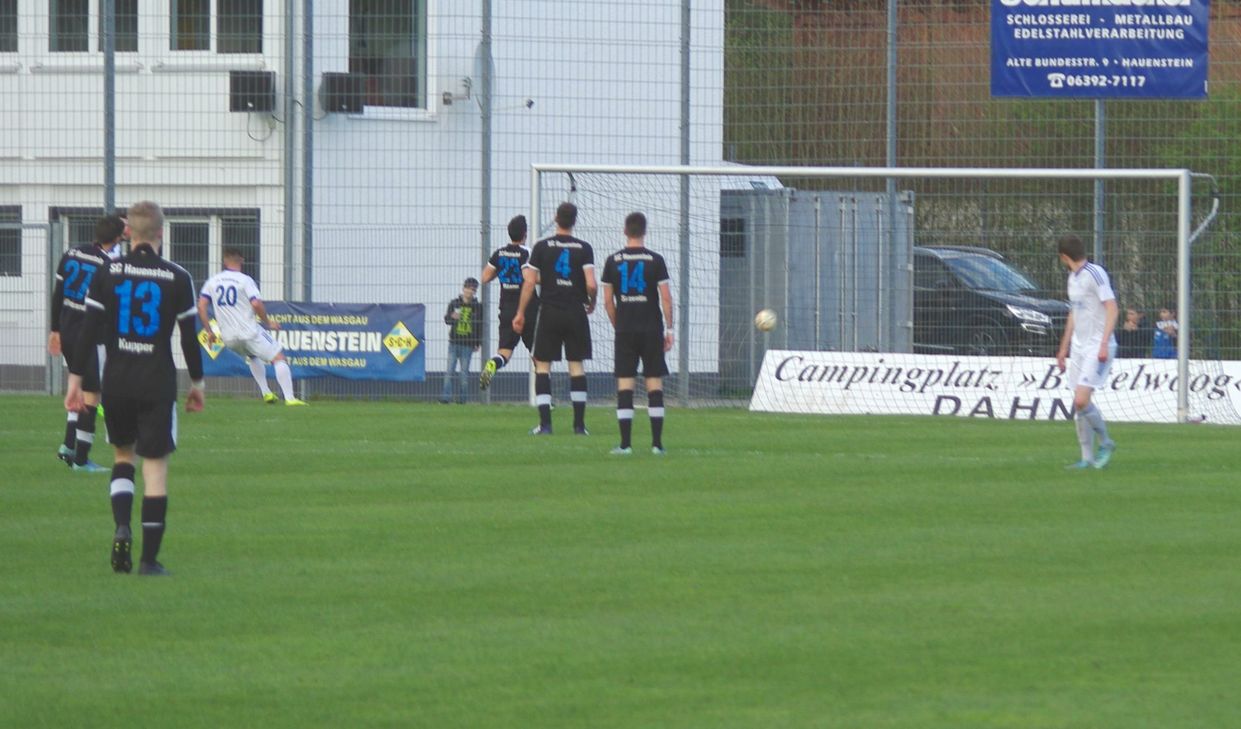 Enrico Köppen (li., weißes Trikot 20) setzt den Ball zum 0:1 für Karbach ins Hauensteiner Tor. Die Abwehr der Gastgeber kann nur zuschauen. Am Ende aber verloren die Karbacher dann doch mit 2:1. Foto: Arno Boes