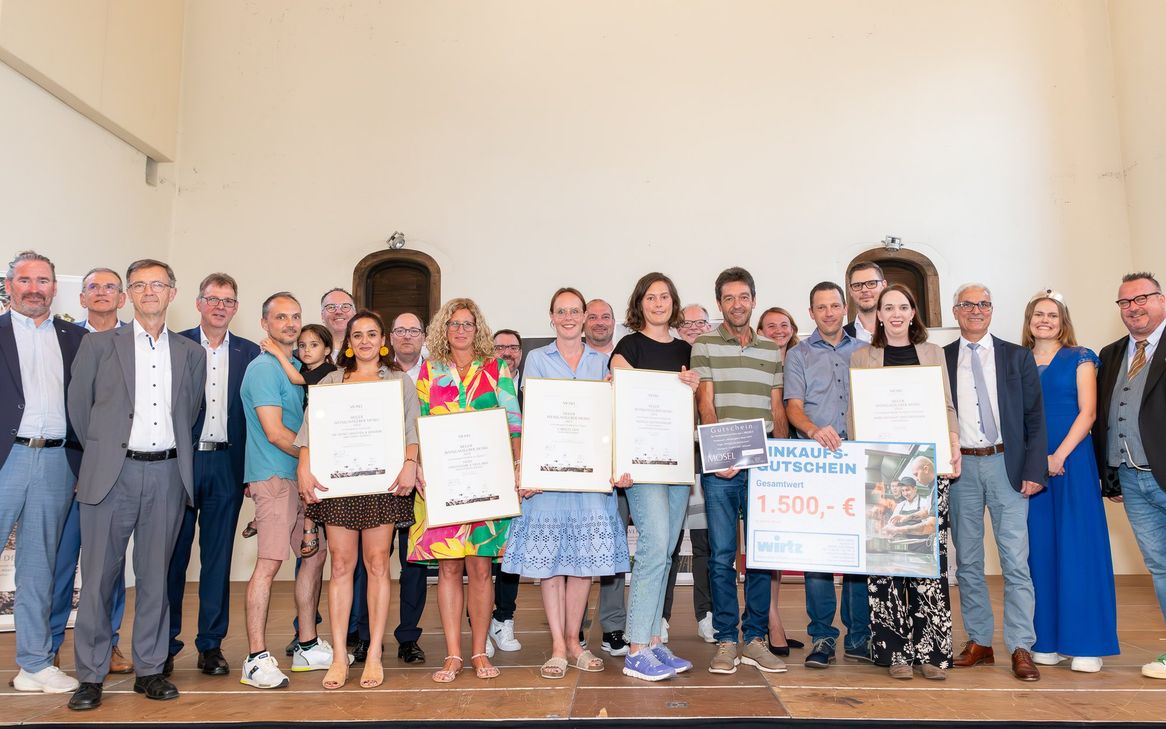 Das Foto zeigt die Sieger mit Staatssekretär Andy Becht (rechts) und Mosel-Weinkönigin Marie-Sophie Schwarz, den Preisstiftern sowie den Vertretern der Wettbewerbsträger im Kulturzentrum Kapuzinerkloster Cochem.