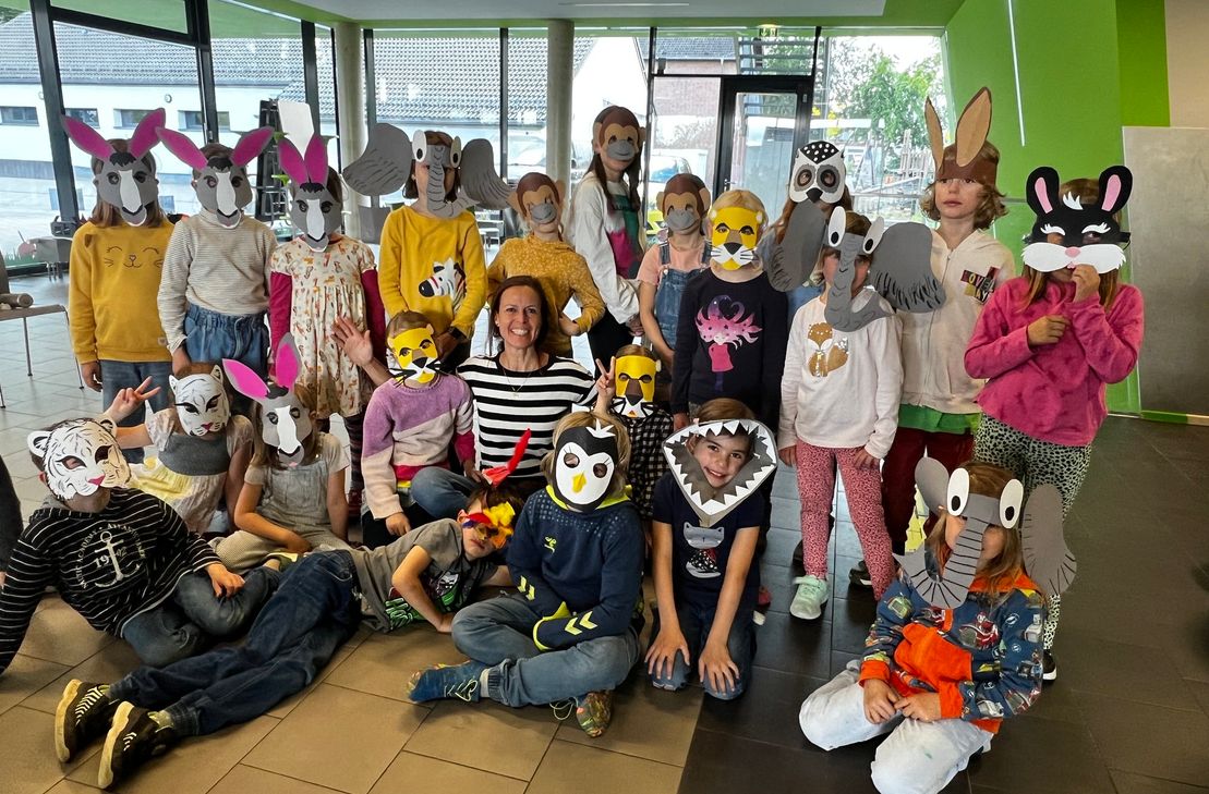 Claudia Steffan (unten Mitte) und die Kinder der Grundschule Roetgen präsentieren stolz ihre selbstgebastelten Masken für das Musiktheaterstück »Karneval der Tiere«.