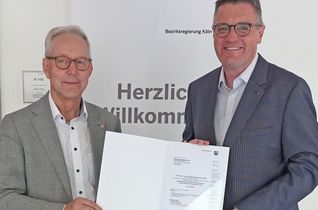 Der Kölner Regierungspräsident Gregor Lange und Städteregionsrat Dr. Tim Grüttemeier mit dem Förderbescheid.