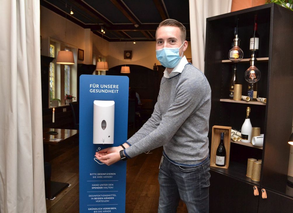 Restaurantleiter Janosch Müller macht es vor: Am Eingang zur "Blauen Ecke" müssen sich alle die Hände desinfizieren. Foto: Mager