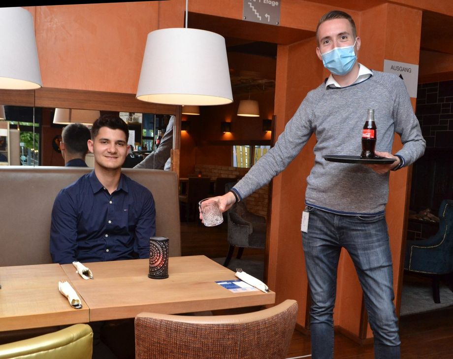 Möglichst viel Abstand hält Restaurantleiter Janosch Müller (r.) beim Servieren. Foto: Mager