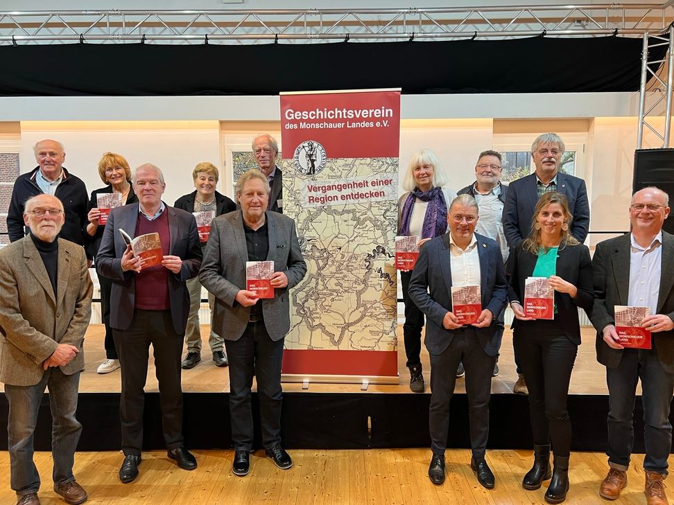 Der Vorstand des Geschichtsvereins des Monschauer Landes um Gabriele Harzheim (hinten, 3.v.r.), Vertreter der lokalen Politik und des Weiss-Verlags, präsentieren das neue »Heimatjahrbuch« im Rotter Saal Hütten.