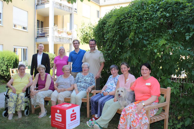 Hinten, v.l.:Jan-Eric Schuetze (Sparkasse Mittelmosel), Silvia Heimes (Heizung und Sanitär Heimes), Philipp Hanke (Johannes Apotheke) und Christian May (Möbel May) haben fünf Gartenbänke an das Seniorenzentrum St. Hedwig gespendet. Vorne v.l.: Heimbeirat Anna Elisabeth Benneker, Marlene Amlinger, Irmgard Hammes, Elise Schneider, Alice Müller, Pflegedienstleitung Angela Brinkmann, Hund Bernie und Einrichtungsleitung Maureen Nuppeney.