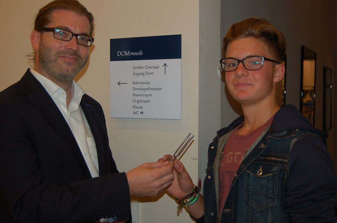 Domkapellmeister Thomas Kiefer überreicht Jona Knopp zum Abschied eine Stimmgabel und wünscht ihm viel Erfolg. Foto: Andreas Arens