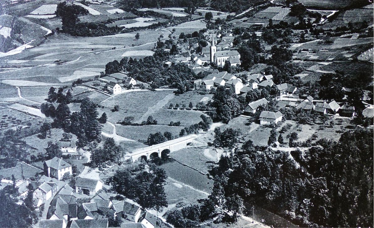 Vor der Aufstockung der Rurtalsperre waren Einruhr und Pleushütte (im unteren Bildteil links der Brücke) nur durch die Rur getrennt. 1958 versank Pleushütte dann in den Fluten. Repro: Hoffmann