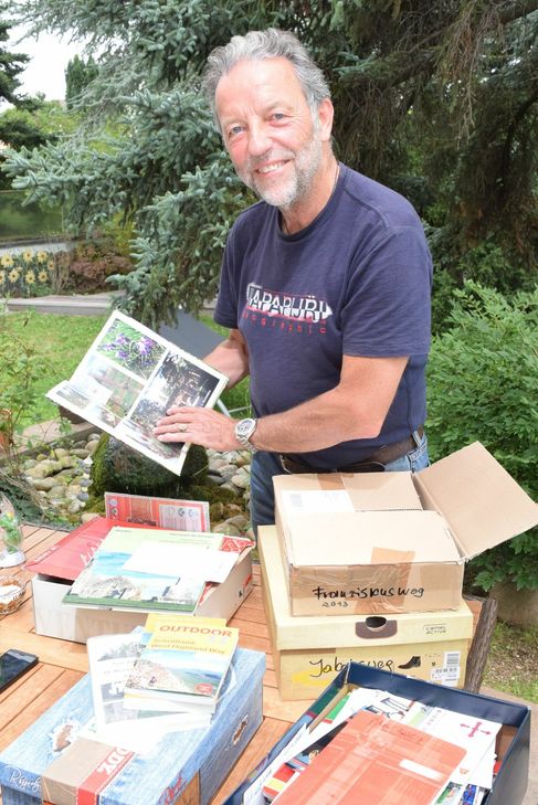 Auf all seinen Pilgertouren hat Gerd Weinand Fotos gemacht und Andenken gesammelt, die er in Kartons aufbewahrt. Foto: Breuer