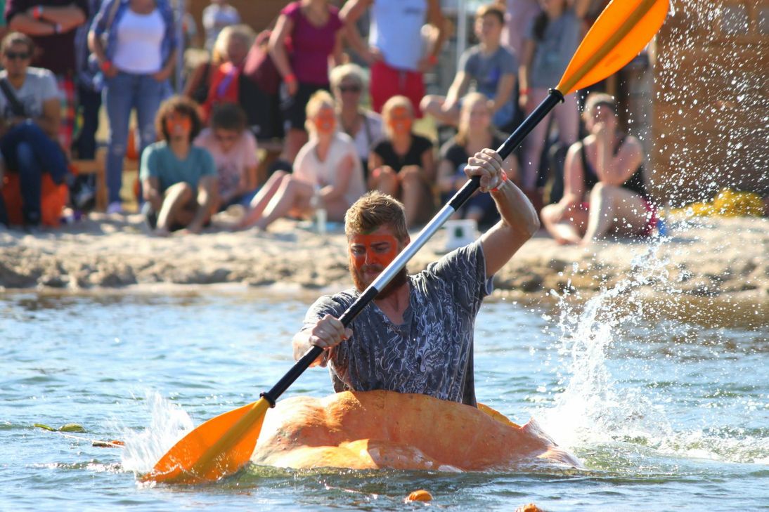 Mit einem Stechpaddel bewaffnet, steigen die mutigen Kürbiskapitäne in ihre Kürbisboote und paddeln auf dem Krewelshofer See um den Sieg. Foto: Krewelshof