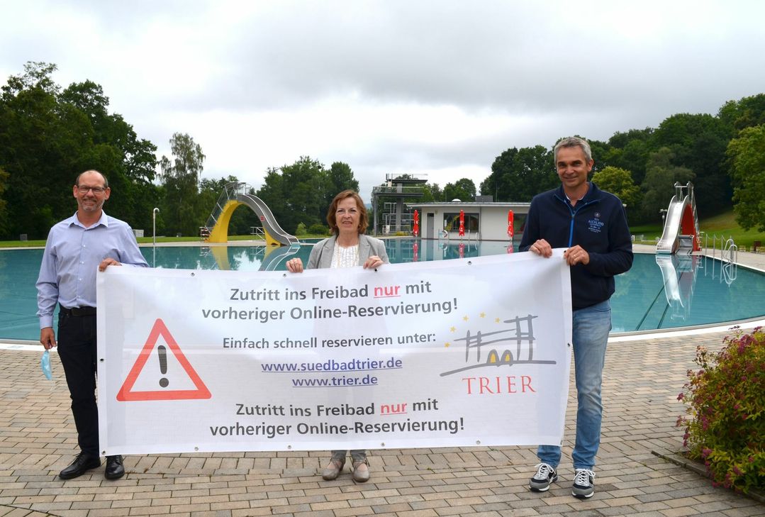 Der Banner wird im Bereich des Südbad-Parkplatzes angebracht. V.l.: Frank Brandscheid (Betriebsleiter Südbad), Bürgermeisterin Elvira Garbes und Matthias Ulbrich (Abteilungsleiter Sport vom Amt Schulen und Sport).