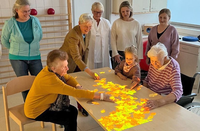 Die Tovertafel zieht Alt und Jung in ihren Bann. Hier lässt es sich auch Andrea Gebhardt vom Fördererverein (3. von links), nicht nehmen, mitzuspielen. Chefärztin Dr. (CS) Janka Matejka (Mitte) und Vertreterinnen ihres Teams freuen sich über das hochmoderne Therapiegerät, das dank einer großzügigen Spende der Else Schütz Stiftung für die Akutgeriatrie in Boppard erworben werden konnte.